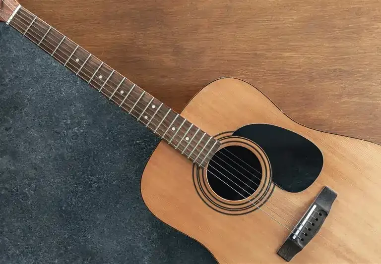 acoustic-guitar-textured-black-wooden-background-top-view